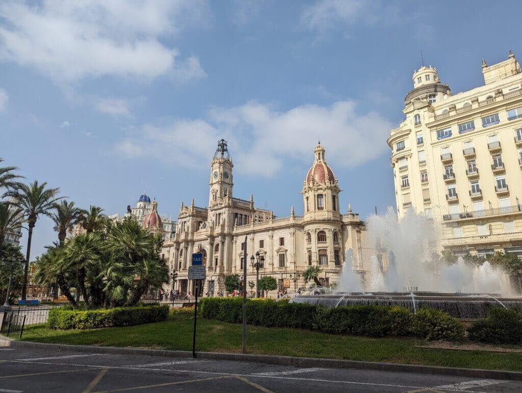 Photo of the Valencia City Hall Square with the fountain and palm trees in front. 