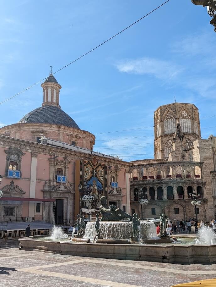 Fountain and basilica in Plaça de la Mare de Déu with people enjoying the evening