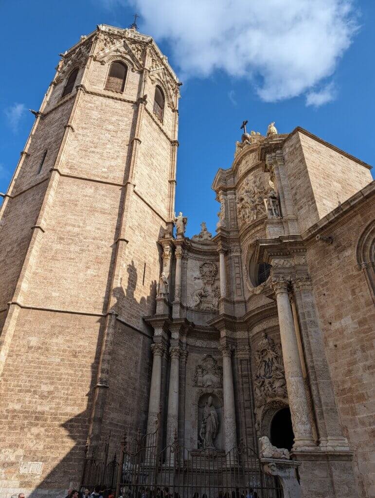 Exterior view of Valencia Cathedral and El Miguelete bell tower under a blue sky
