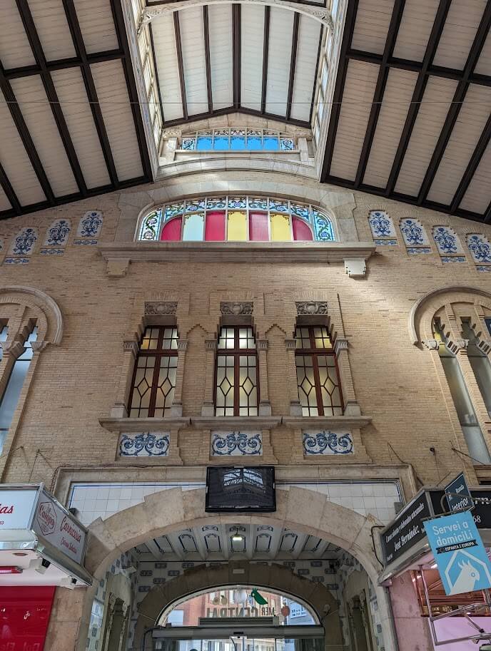 Interior of Mercat Central with stained glass windows and colorful produce stalls